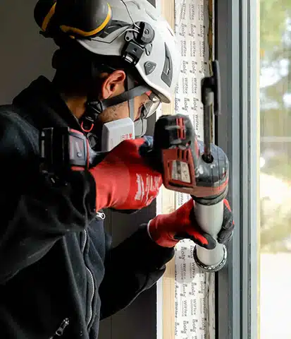 En ansatt som trolig fuger et vindu.